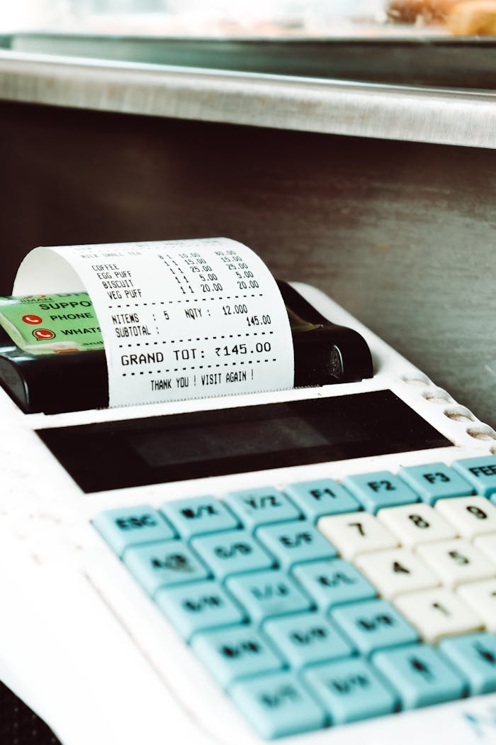 Close-up shot of a cash register printing a receipt with a card nearby, in a retail store.