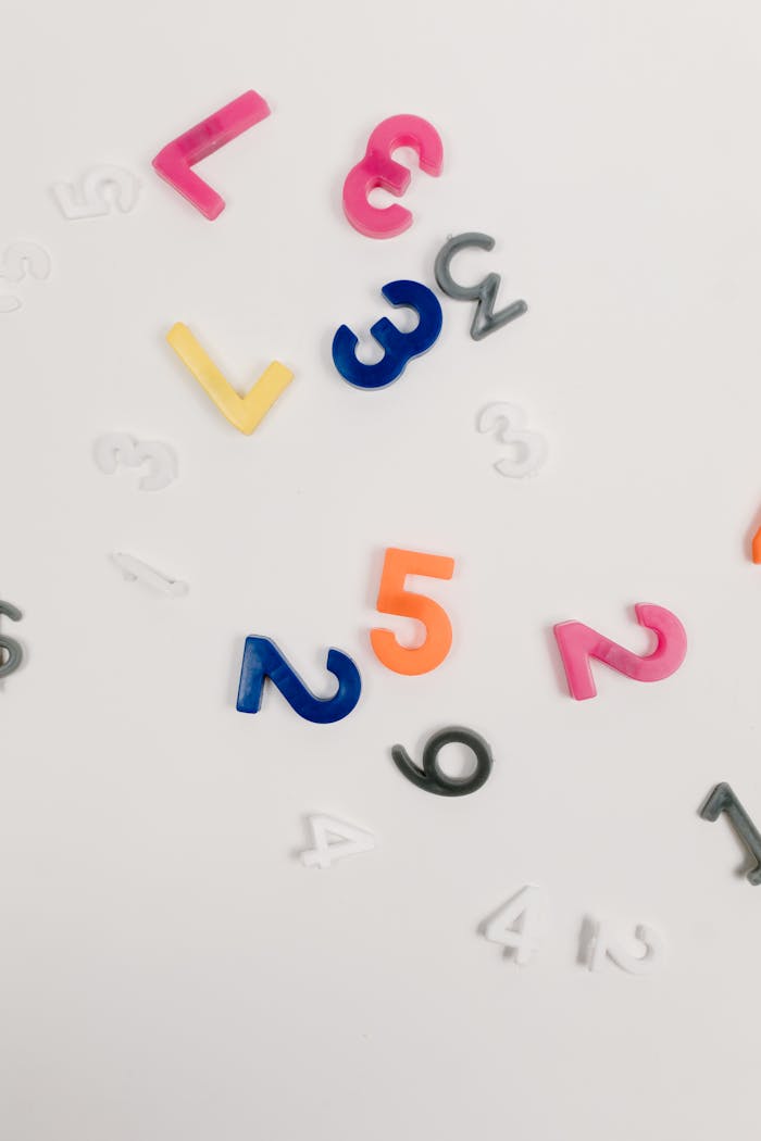Brightly colored plastic numbers scattered on a white surface, ideal for educational and creative concepts.
